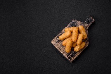 Fast food peynirli çubuklar, koyu beton arka planda tuz ve baharatlar.