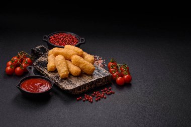 Fast food peynirli çubuklar, koyu beton arka planda tuz ve baharatlar.