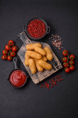 Fast food peynirli çubuklar, koyu beton arka planda tuz ve baharatlar.