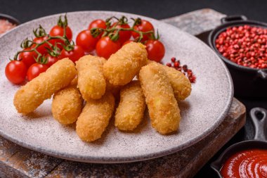 Fast food peynirli çubuklar, koyu beton arka planda tuz ve baharatlar.
