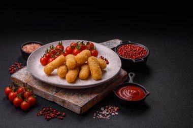 Fast food peynirli çubuklar, koyu beton arka planda tuz ve baharatlar.