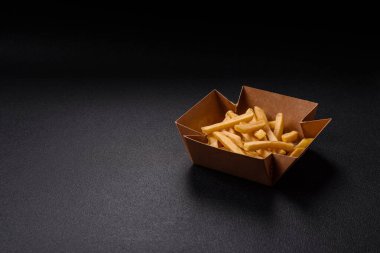 Fast food patates kızartması. Tuz ve baharatla birlikte koyu beton bir arka planda.