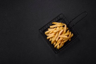 Fast food patates kızartması. Tuz ve baharatla birlikte koyu beton bir arka planda.