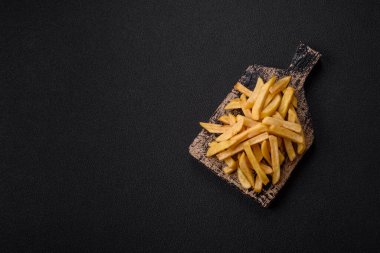 Fast food patates kızartması. Tuz ve baharatla birlikte koyu beton bir arka planda.