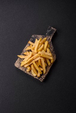 Fast food patates kızartması. Tuz ve baharatla birlikte koyu beton bir arka planda.