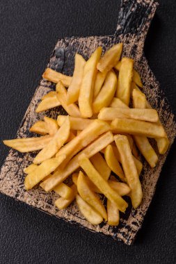 Fast food patates kızartması. Tuz ve baharatla birlikte koyu beton bir arka planda.