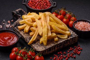 Fast food patates kızartması. Tuz ve baharatla birlikte koyu beton bir arka planda.