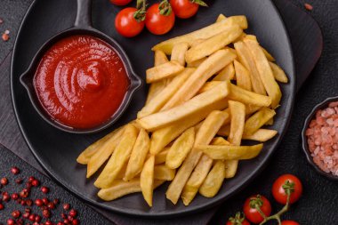 Fast food patates kızartması. Tuz ve baharatla birlikte koyu beton bir arka planda.