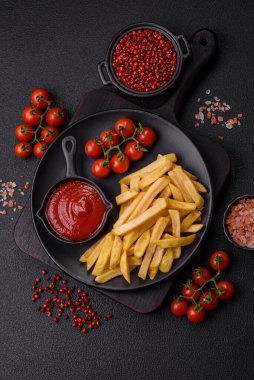 Fast food patates kızartması. Tuz ve baharatla birlikte koyu beton bir arka planda.