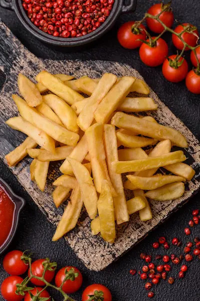 Fast food patates kızartması. Tuz ve baharatla birlikte koyu beton bir arka planda.
