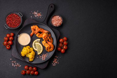 Beyaz soslu haşlanmış kaplan karidesleri ve koyu beton arka planda limon.