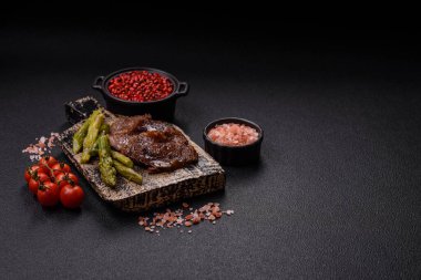 Kaynamış kuşkonmaz, tuz ve baharatla kesilmiş sulu sığır eti ya da domuz eti koyu beton arka planda.