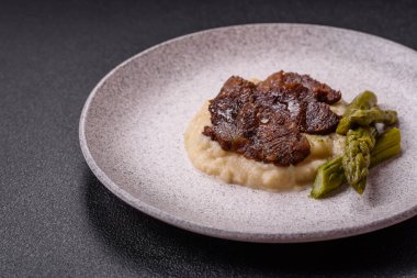 Kaynamış kuşkonmaz, tuz ve baharatla kesilmiş sulu sığır eti ya da domuz eti koyu beton arka planda.