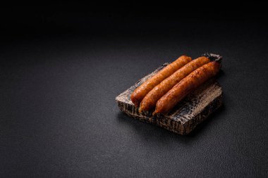 Koyu beton bir arka planda tuzlu, baharatlı ve otlu kızarmış biftek veya domuz sosisi.