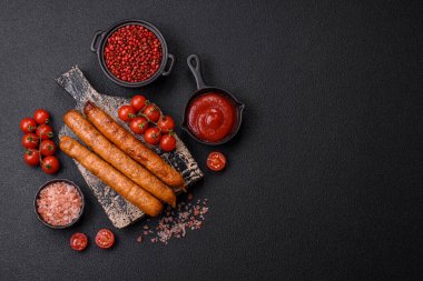 Koyu beton bir arka planda tuzlu, baharatlı ve otlu kızarmış biftek veya domuz sosisi.