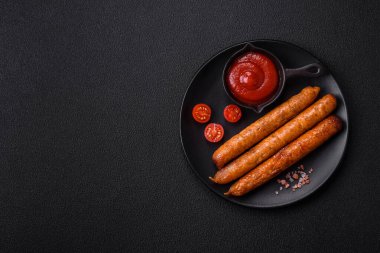 Koyu beton bir arka planda tuzlu, baharatlı ve otlu kızarmış biftek veya domuz sosisi.