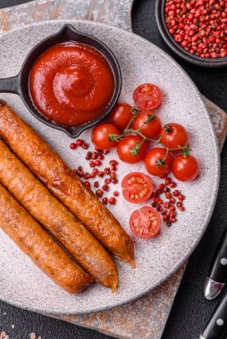 Koyu beton bir arka planda tuzlu, baharatlı ve otlu kızarmış biftek veya domuz sosisi.