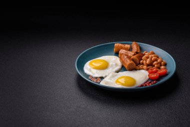 Haşlanmış yumurta, fasulye, sosis, domates, tuz ve baharatlı koyu beton arka planda tam İngiliz kahvaltısı.