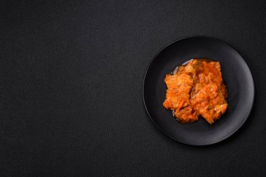 Koyu beton arka planda tuz ve baharatla domates soslu dilimlenmiş balık.