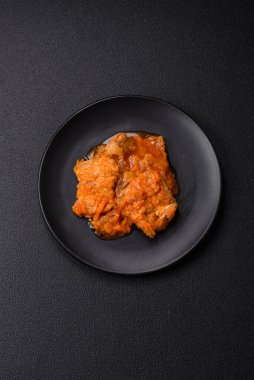 Koyu beton arka planda tuz ve baharatla domates soslu dilimlenmiş balık.