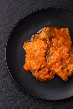 Koyu beton arka planda tuz ve baharatla domates soslu dilimlenmiş balık.