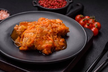 Koyu beton arka planda tuz ve baharatla domates soslu dilimlenmiş balık.