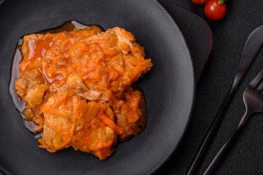 Koyu beton arka planda tuz ve baharatla domates soslu dilimlenmiş balık.