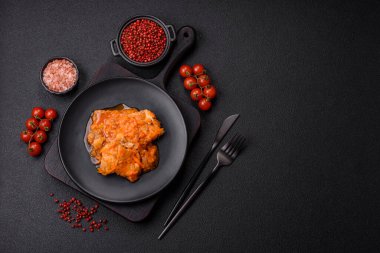 Koyu beton arka planda tuz ve baharatla domates soslu dilimlenmiş balık.