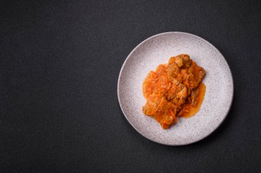 Koyu beton arka planda tuz ve baharatla domates soslu dilimlenmiş balık.