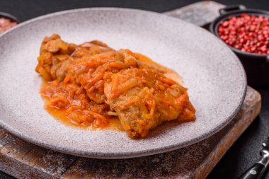 Koyu beton arka planda tuz ve baharatla domates soslu dilimlenmiş balık.