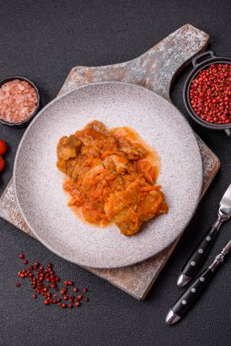 Koyu beton arka planda tuz ve baharatla domates soslu dilimlenmiş balık.