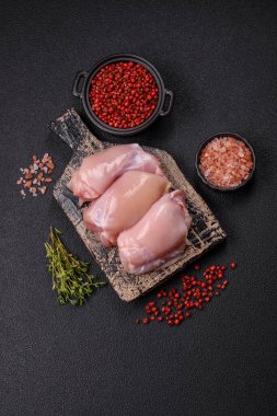 Koyu beton bir masada baharat ve otlarla taze tavuk filetosu. Et yemekleri için hazırlık.