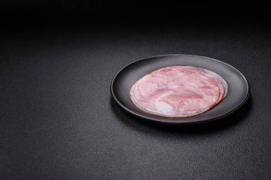 Koyu dokulu arka planda tuz, baharat ve otlarla dilimlenmiş jambon.