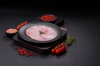 Koyu dokulu arka planda tuz, baharat ve otlarla dilimlenmiş jambon.