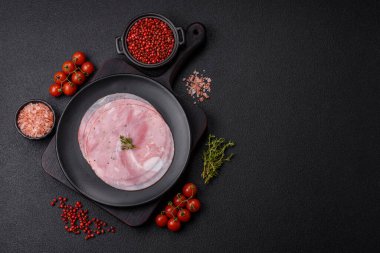 Koyu dokulu arka planda tuz, baharat ve otlarla dilimlenmiş jambon.