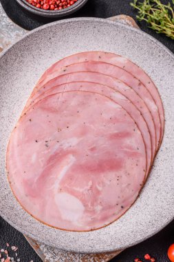 Koyu dokulu arka planda tuz, baharat ve otlarla dilimlenmiş jambon.