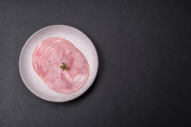 Koyu dokulu arka planda tuz, baharat ve otlarla dilimlenmiş jambon.