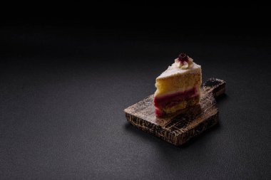 Sweet delicious cake with a layer of raspberry jam sprinkled with coconut on a dark concrete background