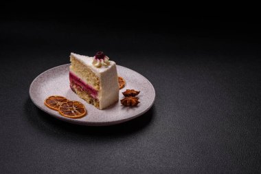 Sweet delicious cake with a layer of raspberry jam sprinkled with coconut on a dark concrete background