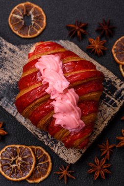 Koyu beton arka planda kremalı ve çilekli taze kırmızı kruvasan.