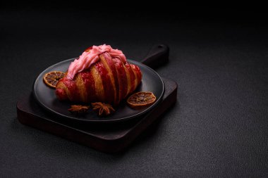 Koyu beton arka planda kremalı ve çilekli taze kırmızı kruvasan.