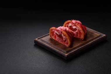 Koyu beton arka planda kremalı ve çilekli taze kırmızı kruvasan.