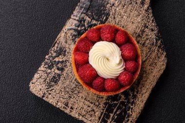 Ahududu ve kremalı tart, koyu dokulu arka planda.