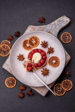 Ahududu ve kremalı tart, koyu dokulu arka planda.