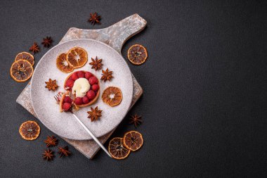 Ahududu ve kremalı tart, koyu dokulu arka planda.