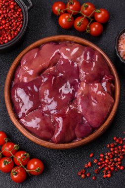 Fresh raw chicken or beef liver with salt, spices and herbs on a dark concrete background clipart