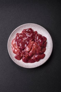 Fresh raw chicken or beef liver with salt, spices and herbs on a dark concrete background clipart