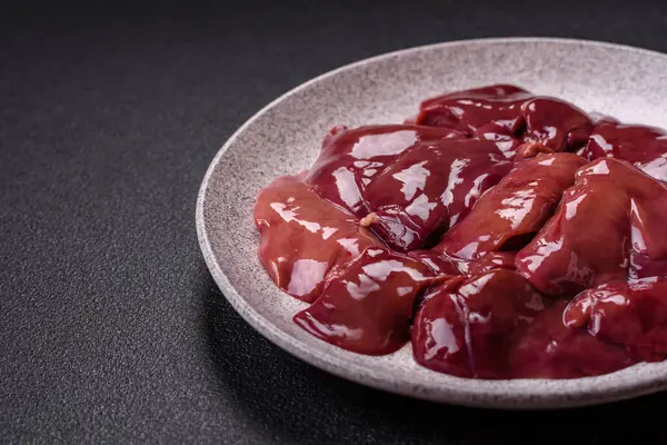 stock image Fresh raw chicken or beef liver with salt, spices and herbs on a dark concrete background