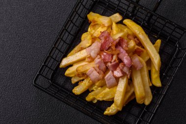 Koyu beton arka planda domuz pastırması, tuz ve baharatla kızarmış patates kızartması.