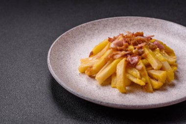 Koyu beton arka planda domuz pastırması, tuz ve baharatla kızarmış patates kızartması.